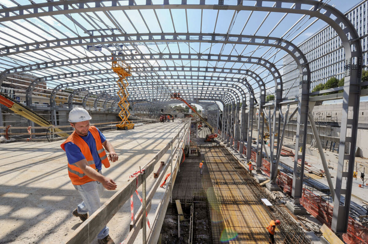 Cantiere edile con tettoia in acciaio e operai al lavoro